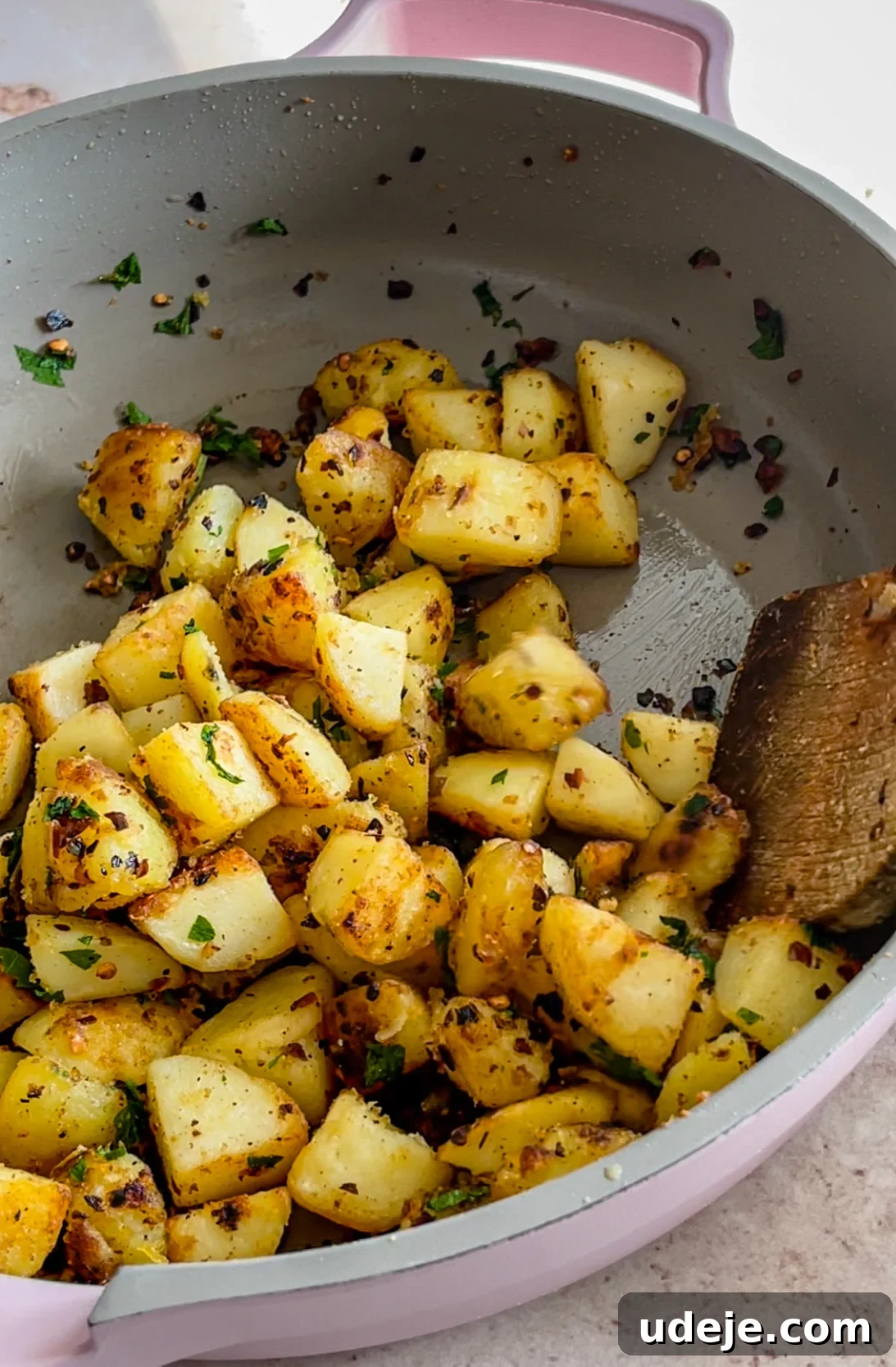 Spicy Golden Crispy Batata Harra 8 Cooked crispy potatoes in a skillet, garnished with chili flakes and parsley