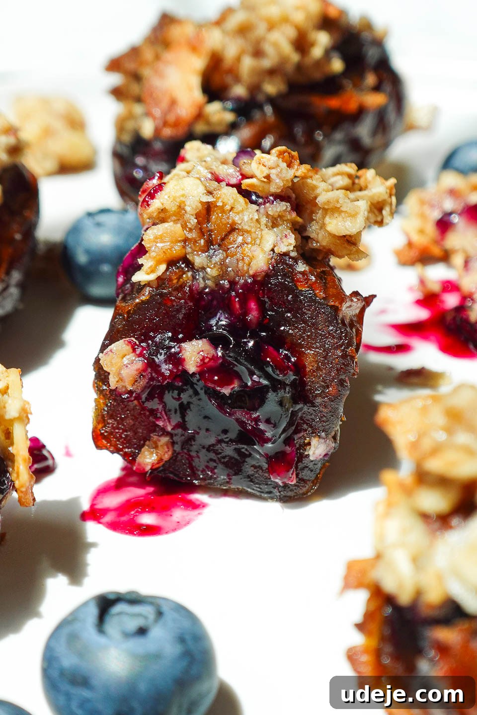 Blueberry Crisp Date Gems 3 Blueberry Crisp Stuffed Date with a bite taken, revealing juicy blueberry compote inside and crunchy oat topping