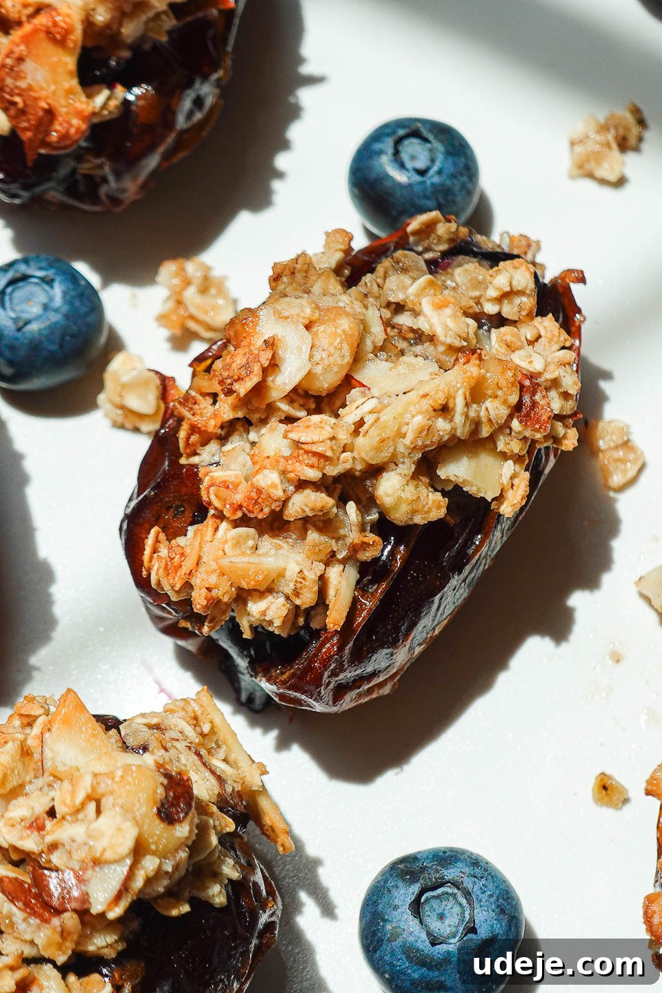 Blueberry Crisp Date Gems 4 Blueberry Crisp Stuffed Dates on a white plate garnished with fresh blueberries for a vibrant presentation