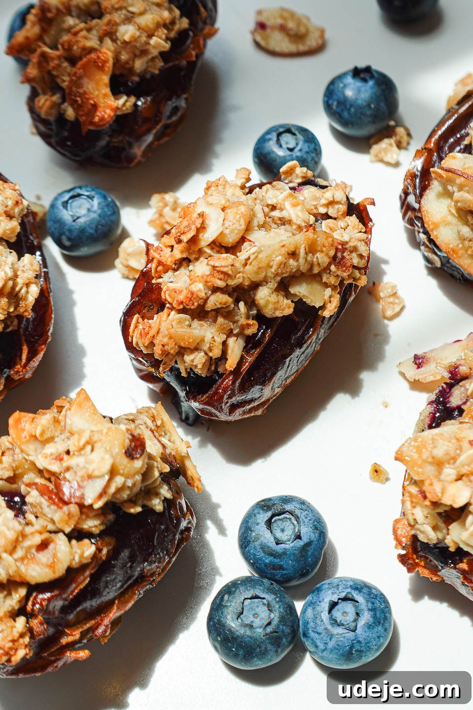 Blueberry Crisp Date Gems 6 Air-fried Blueberry Crisp Stuffed Dates served with fresh blueberries on a white plate, ready for dessert
