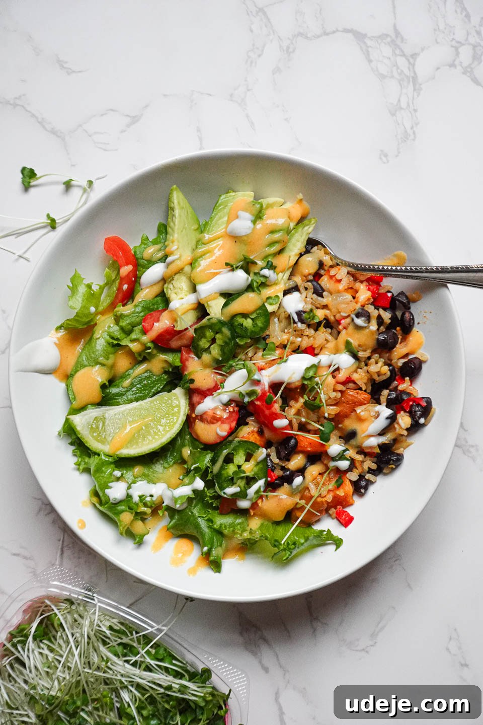 Plant-Powered Sweet Potato Burrito Bowl 2 Overhead shot of a vegan burrito bowl with brown rice, roasted sweet potatoes, black beans, and fresh toppings in a ceramic bowl