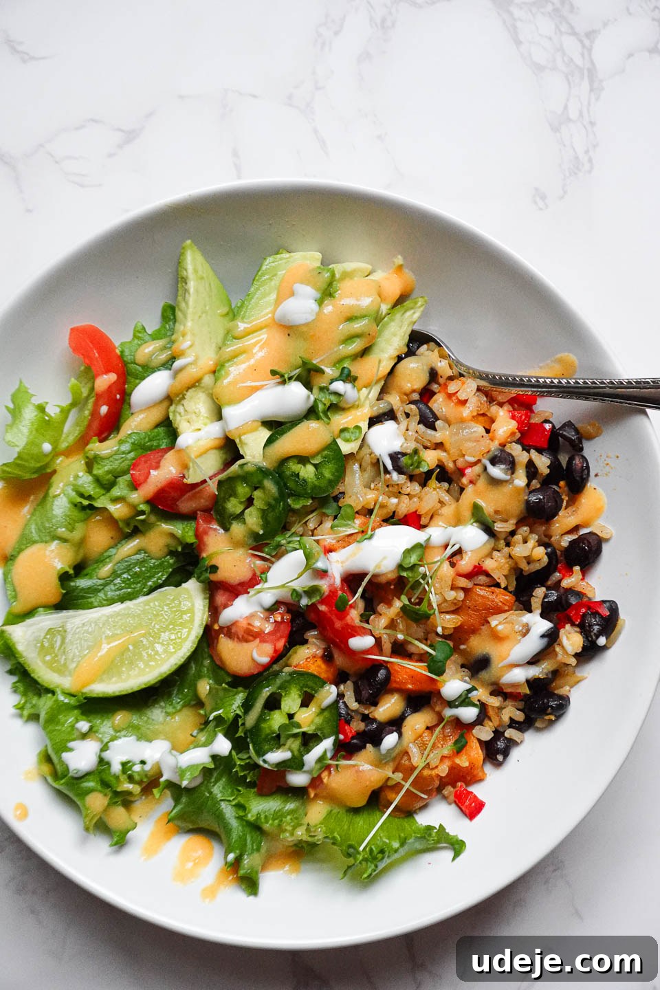 Plant-Powered Sweet Potato Burrito Bowl 4 Plated vegan burrito bowl garnished with lime wedges