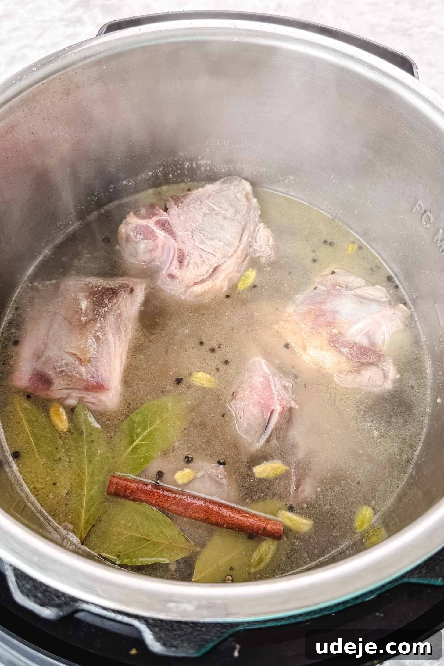 Mansaf: Jordan's Tangy Lamb Masterpiece 6 Lightly browned lamb shoulder in a steel pot with bay leaves, a cinnamon stick, black peppercorns, whole cardamom pods and water.