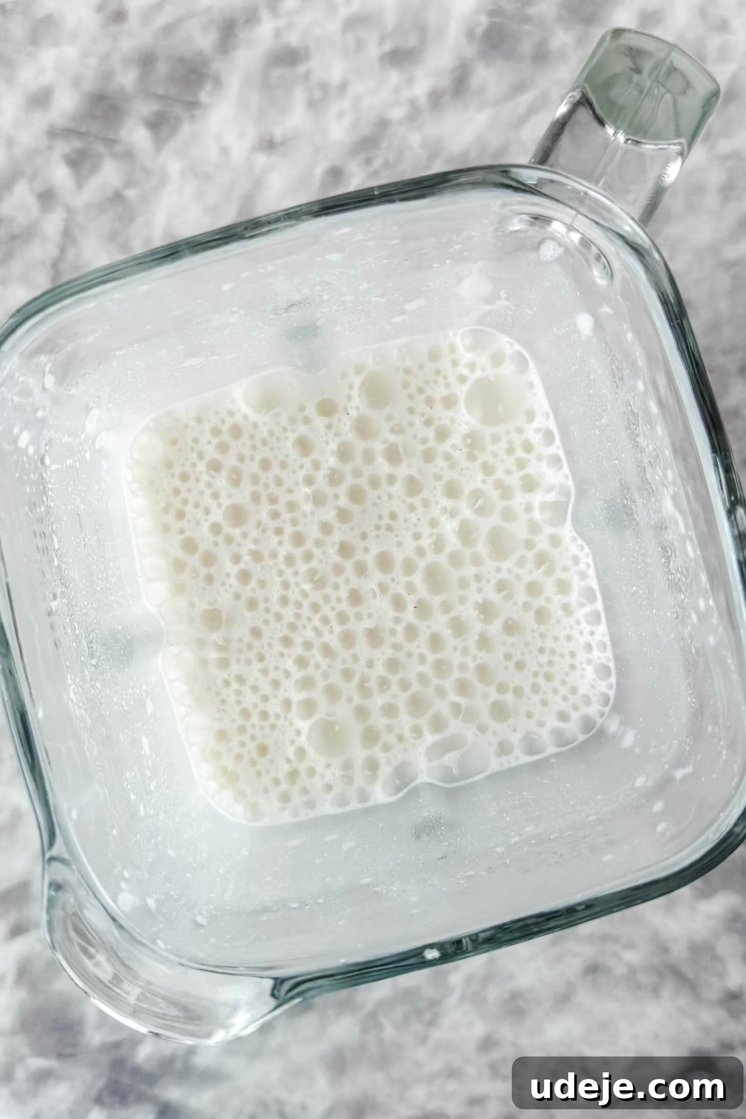 Mansaf: Jordan's Tangy Lamb Masterpiece 10 A glass blender jug with white bubbly liquid over a marble background.