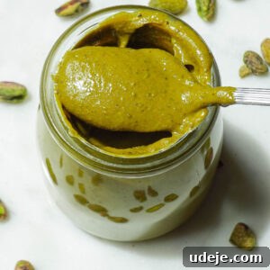 Creamy homemade pistachio butter in a glass jar with spoon
