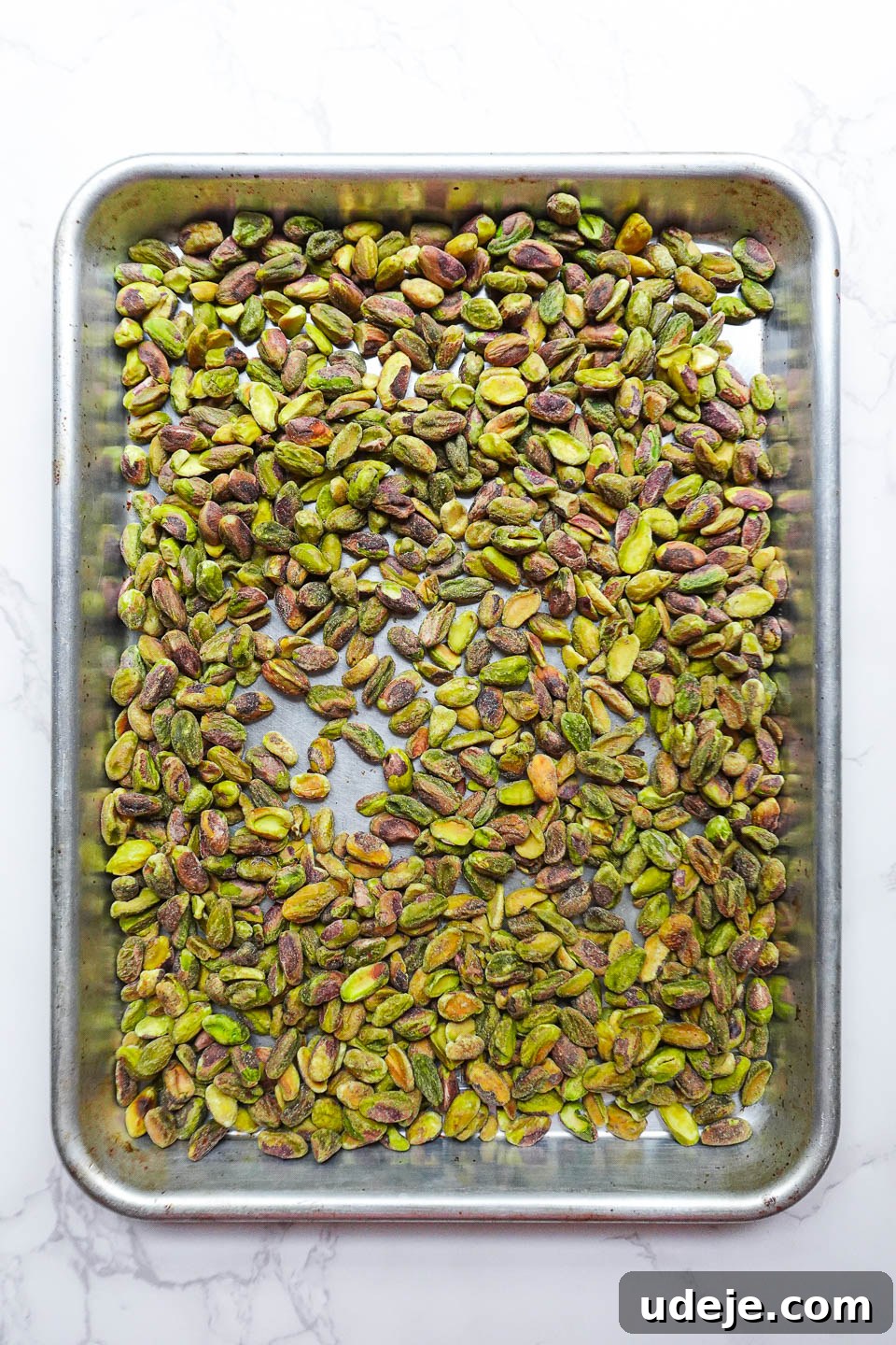 Artisan Pistachio Spread 6 A generous scattering of raw, shelled pistachios spread evenly on a baking tray, ready for a light roast.