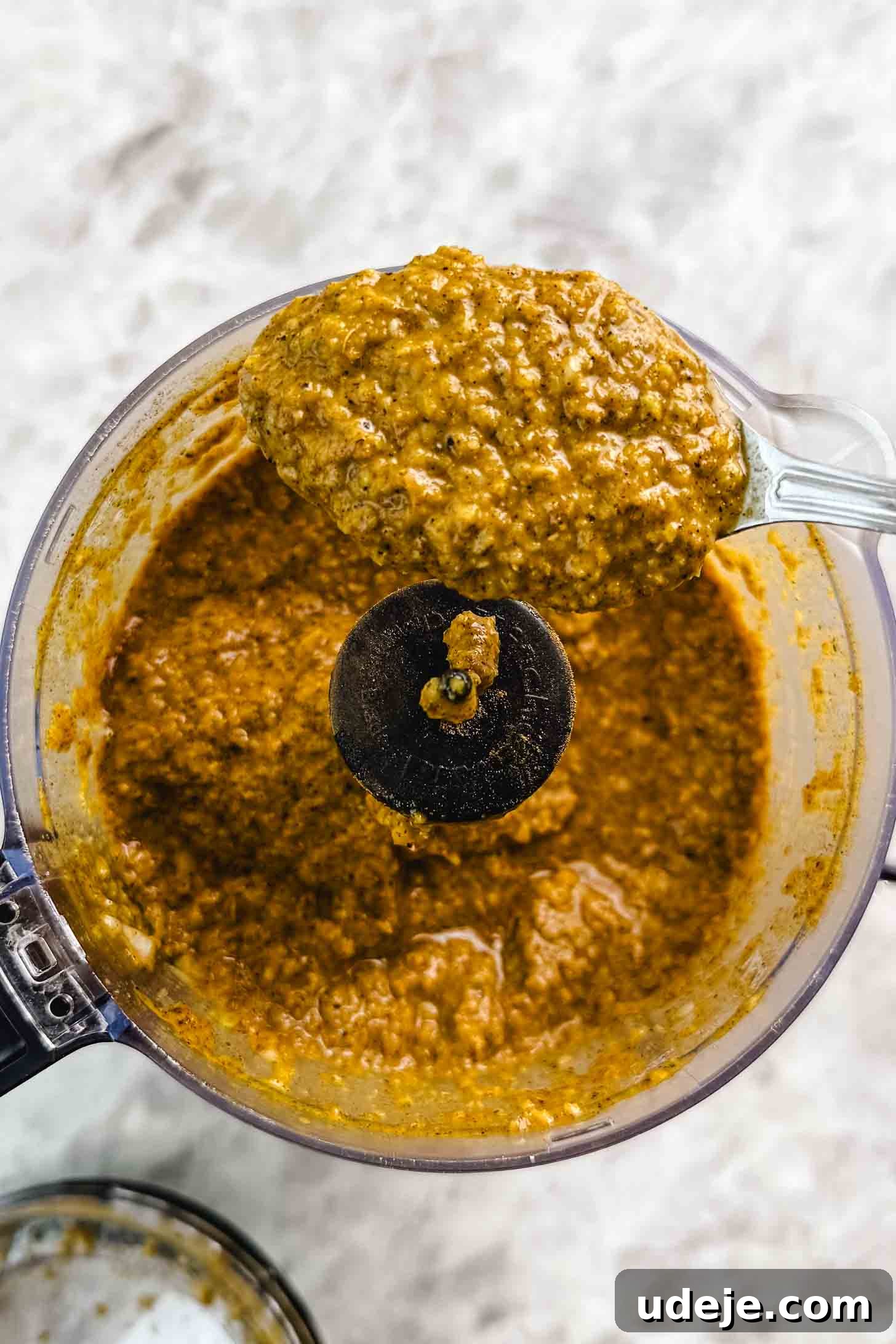 Fall-Apart Tender Lamb Haneeth 5 Small food processor with a brown marinade being held up by a spoon on a marble background.