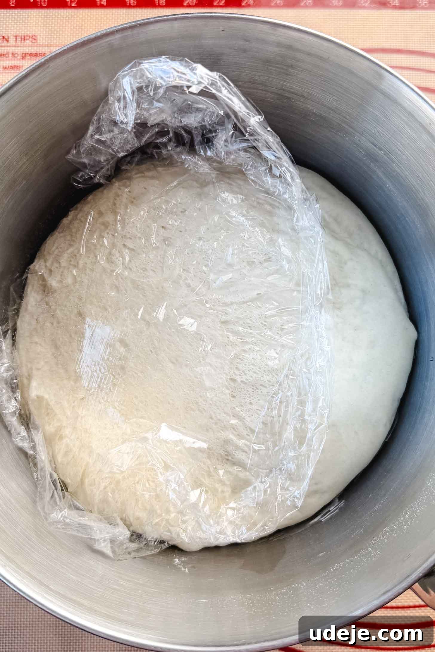Customizable Homemade Turkish Pide 6 A large metal bowl covered with plastic wrap, revealing a significantly risen dough, signifying it has completed its initial proofing stage.