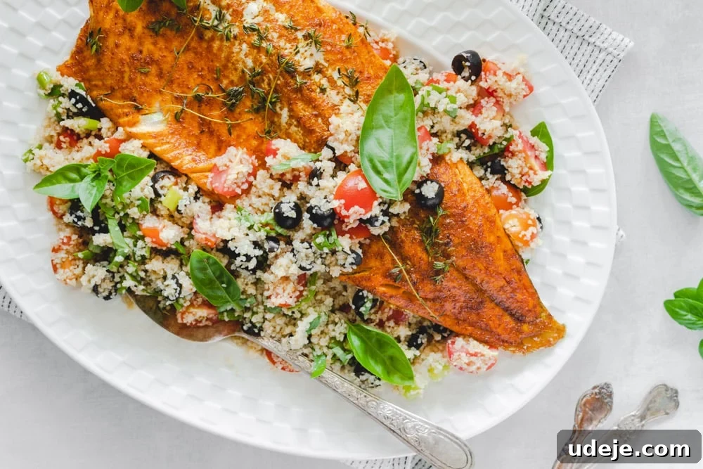 Mediterranean Baked Rainbow Trout with Herbed Bulgur 2 Rainbow trout fillet served over a bed of bulgur salad in a white plate, with a serving spoon and basil