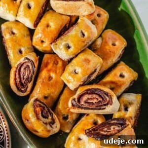 Iraqi Kleicha A Sweet Tradition with Date or Walnut 31 A green platter filled with golden-brown, glossy Kleicha pastries featuring a visible chocolate swirl or filling, neatly arranged in overlapping rows.