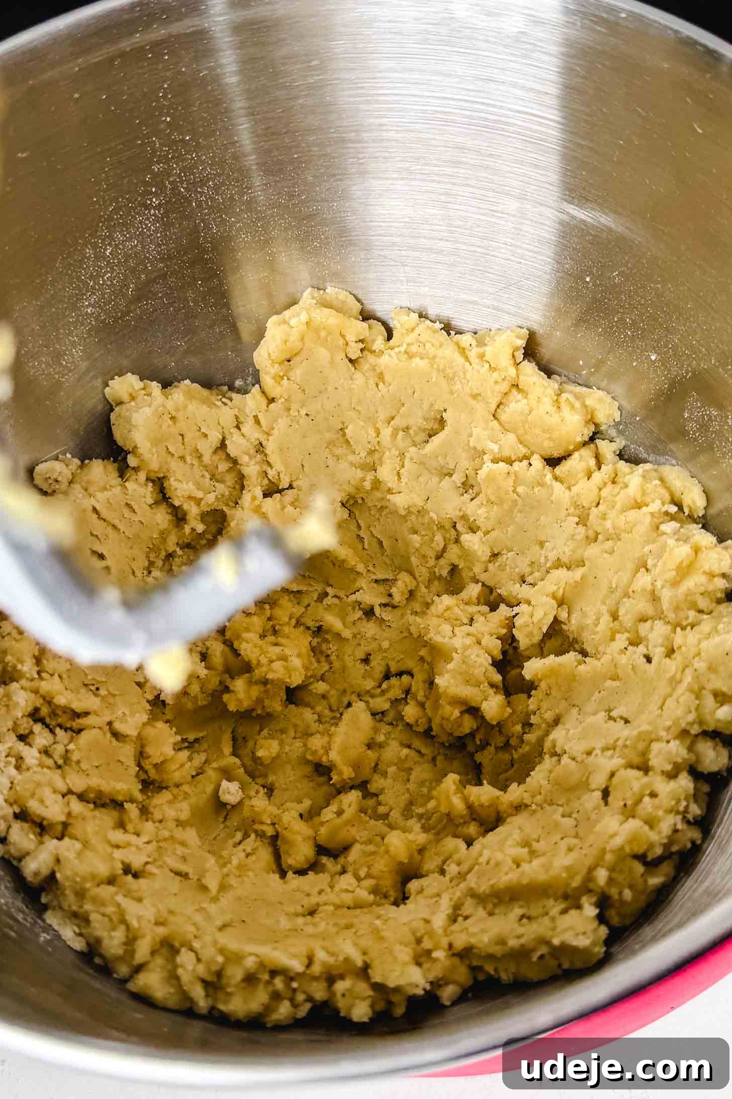 Iraqi Kleicha A Sweet Tradition with Date or Walnut 7 A close-up of a mixing bowl with a paddle attachment, filled with thick, pale yellow Kleicha cookie dough that has just been mixed.