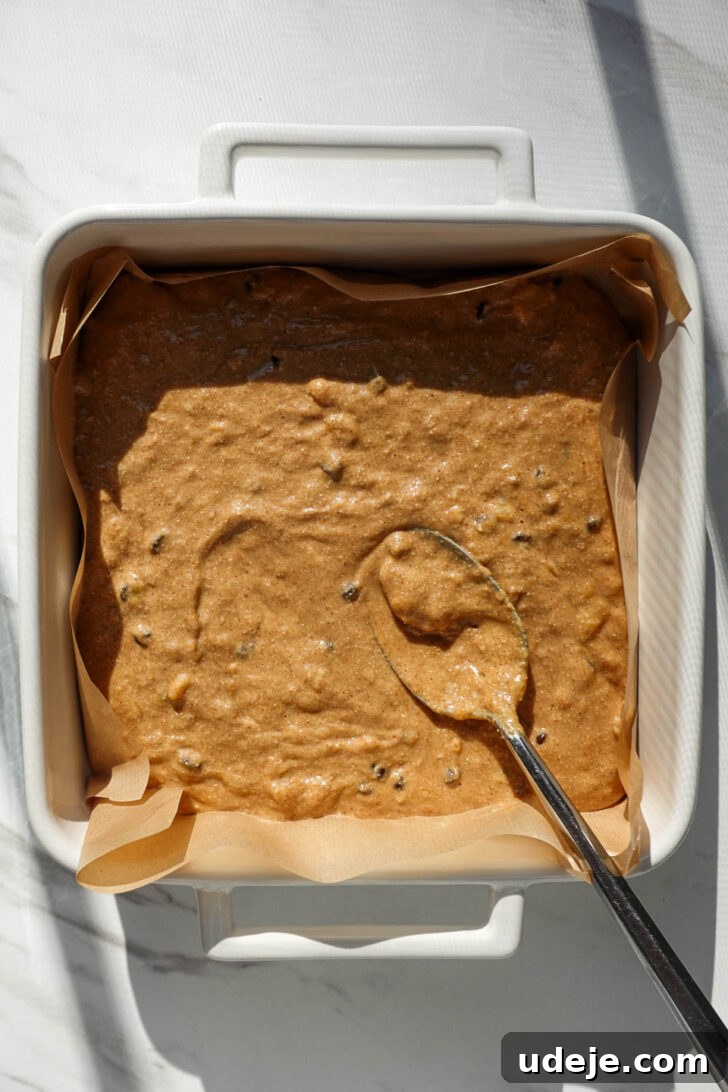 Vegan Gluten Free Chocolate Chip Banana Dream Bars 7 Banana bar batter in a parchment-lined square baking pan, showing the smooth, ready-to-bake consistency.