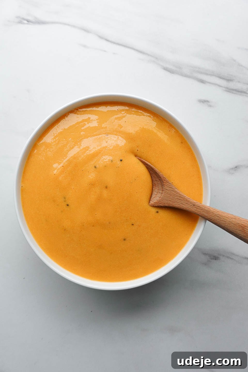 Golden Vegan Cheese Sauce Potato And Carrot Infusion 9 Nut-free vegan cheese sauce made with potatoes and carrots served in a white bowl, ready to enjoy