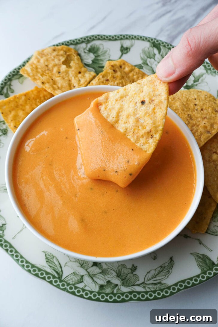 Golden Vegan Cheese Sauce Potato And Carrot Infusion 10 Creamy dairy-free cheese sauce served as a queso dip with tortilla chips on a rustic board