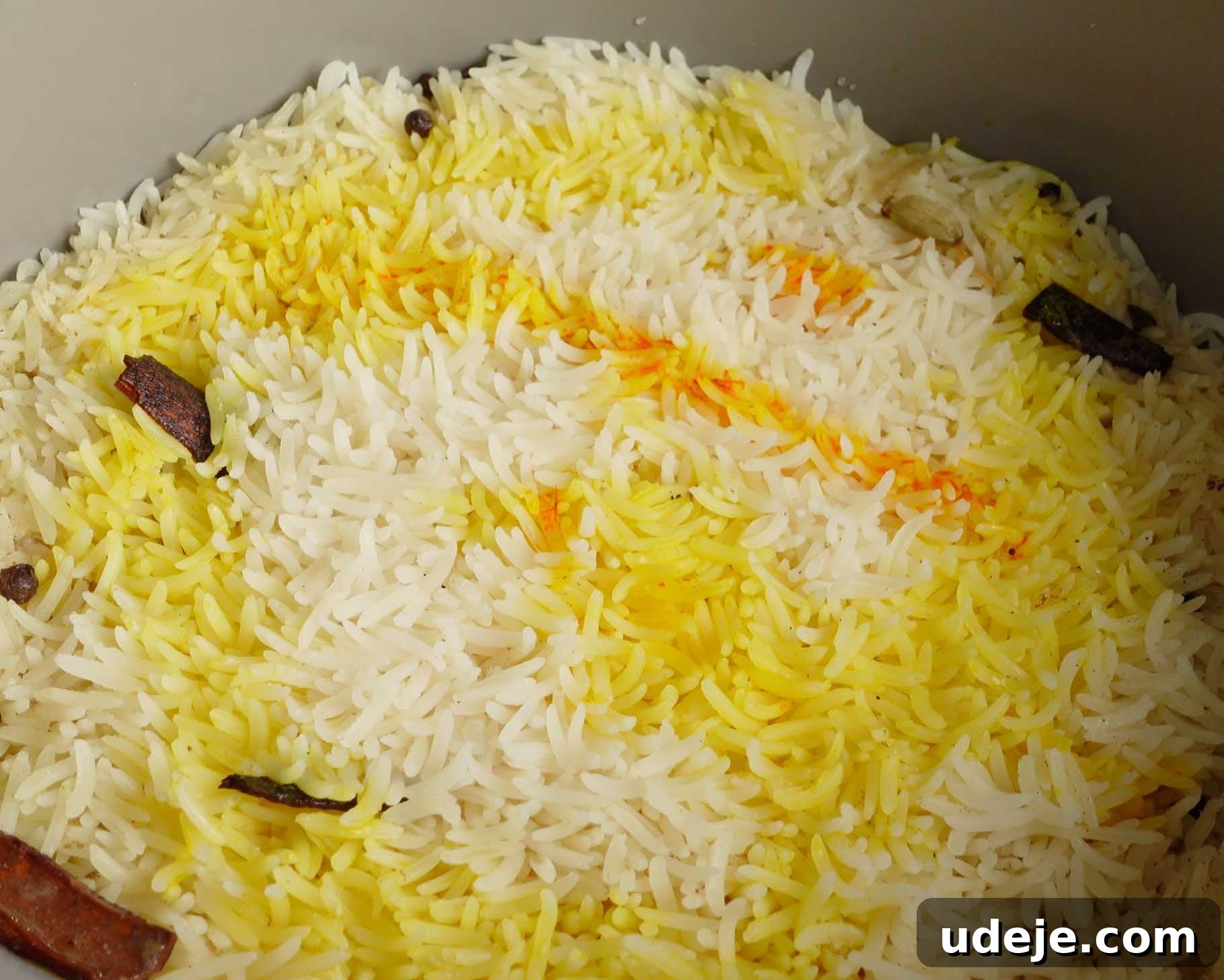 Melt-in-Your-Mouth Yemeni Lamb Mandi 17 A close-up of cooked basmati rice with a mix of white and yellow grains, garnished with whole spices like cinnamon sticks and cloves.