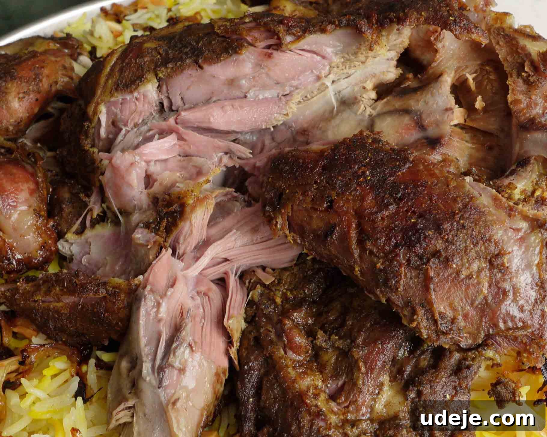 Melt-in-Your-Mouth Yemeni Lamb Mandi 20 Close-up of tender, roasted lamb pieces served on a bed of yellow rice, showing juicy, shredded meat with a browned, seasoned crust.