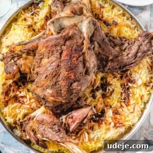 Melt-in-Your-Mouth Yemeni Lamb Mandi 21 A large serving platter holds roasted lamb atop yellow and white rice, garnished with slivered almonds. Small bowls of green sauce and extra plates are visible around the platter.