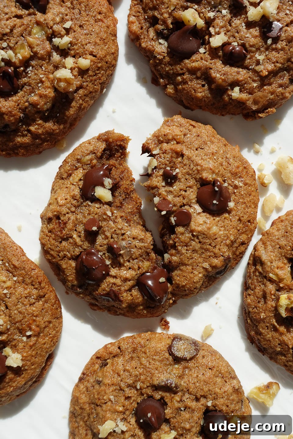 Soft-Baked Vegan Banana Bread Cookies 11 A vegan banana bread cookie thoughtfully cut in half, showcasing its incredibly soft, moist, and chewy interior, complete with visible chocolate chips and crunchy walnut pieces.
