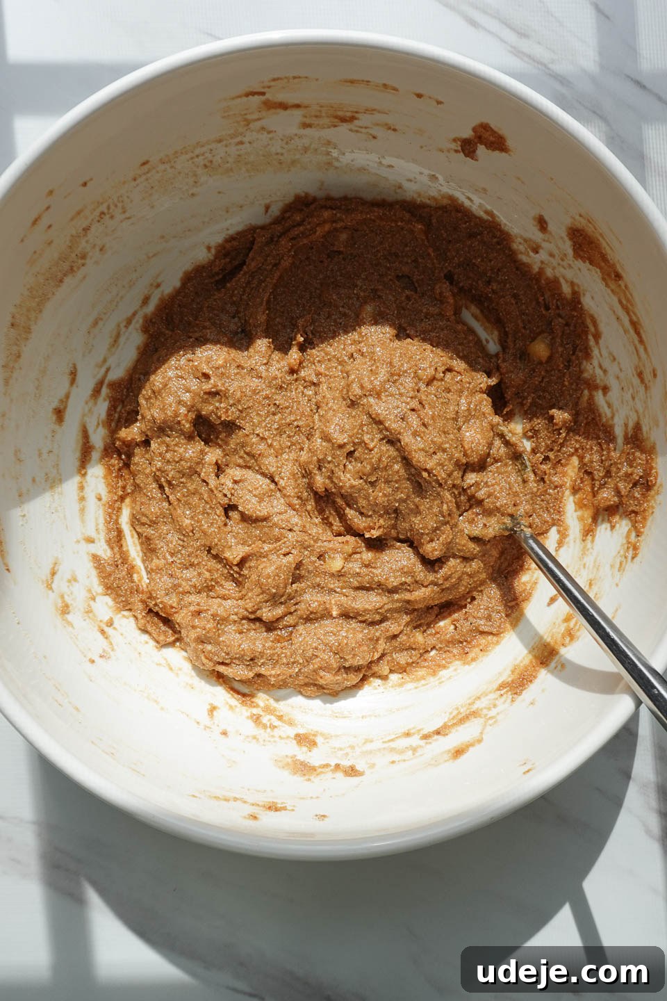 Soft-Baked Vegan Banana Bread Cookies 7 Adding dry ingredients such as almond flour, oat flour, baking soda, ground cinnamon, nutmeg, and salt to the wet banana mixture, preparing for the dough formation.