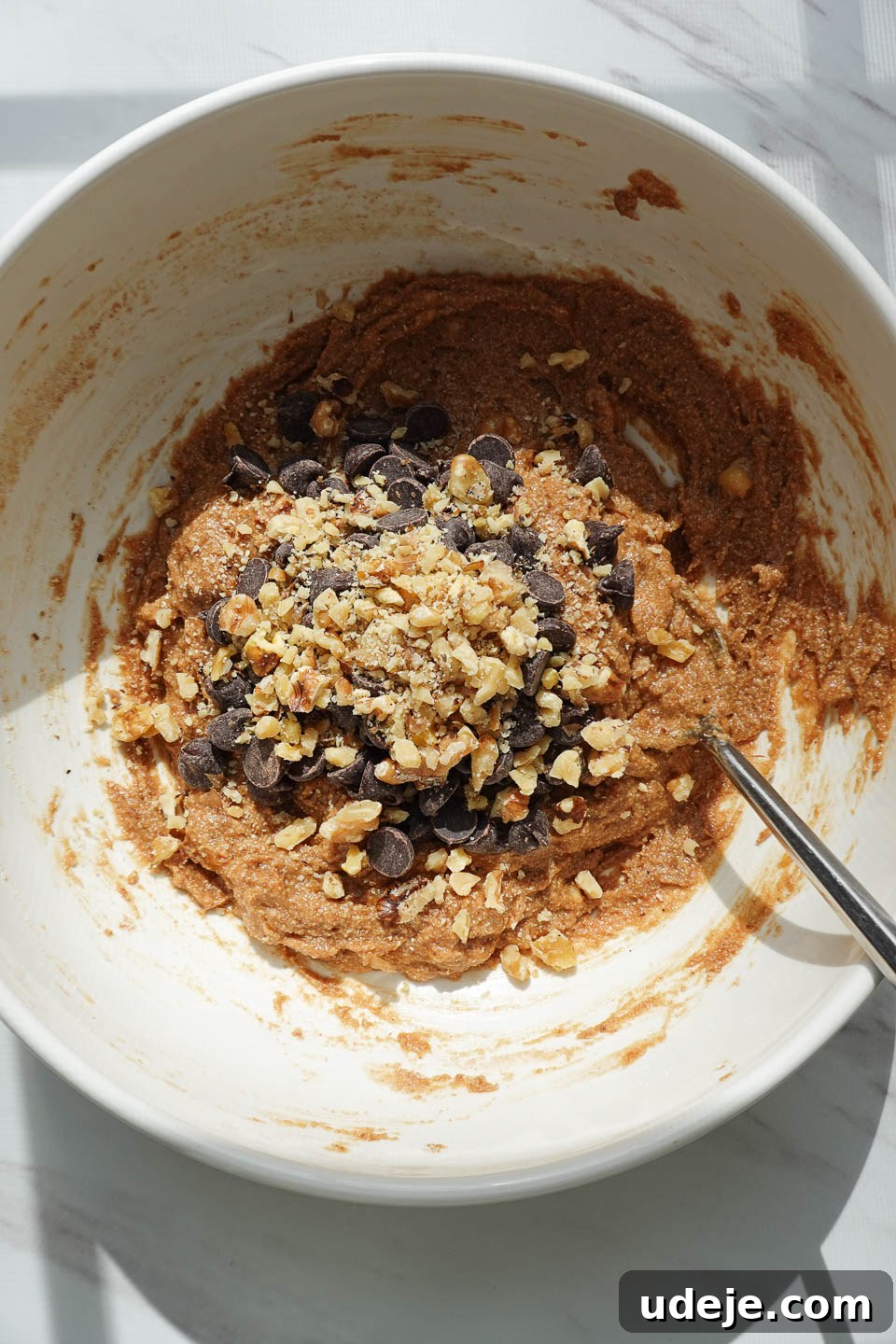 Soft-Baked Vegan Banana Bread Cookies 8 The final stage of dough preparation, gently folding in vegan chocolate chips and crushed walnuts, ensuring an even distribution of delicious mix-ins.