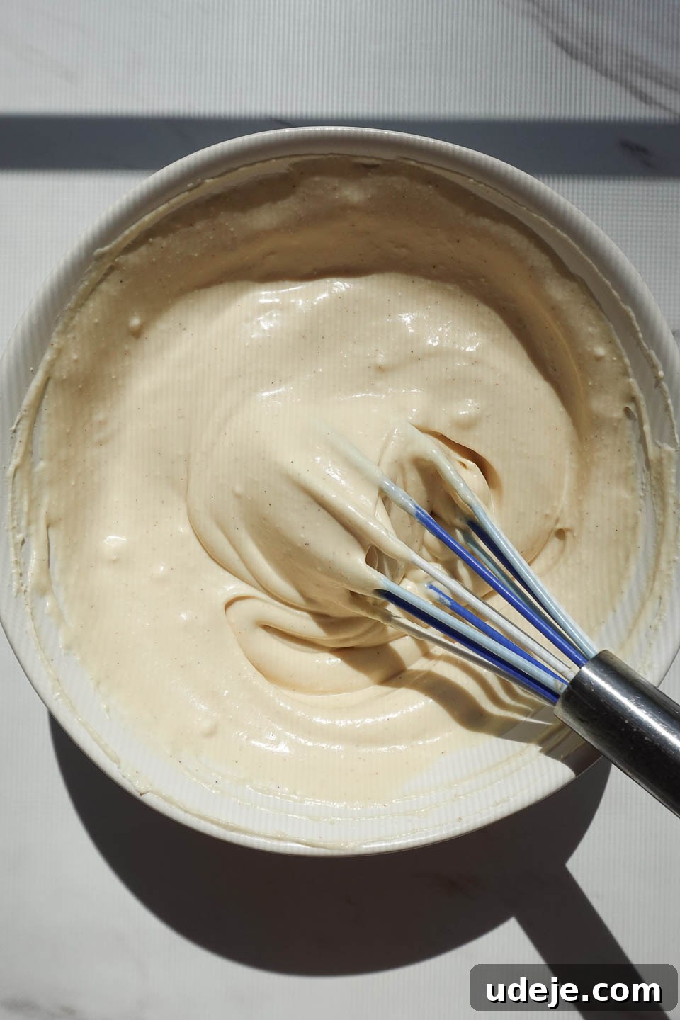 Dreamy No Bake Carrot Cake 13 whisking vegan cream cheese frosting for raw carrot cake in a bowl