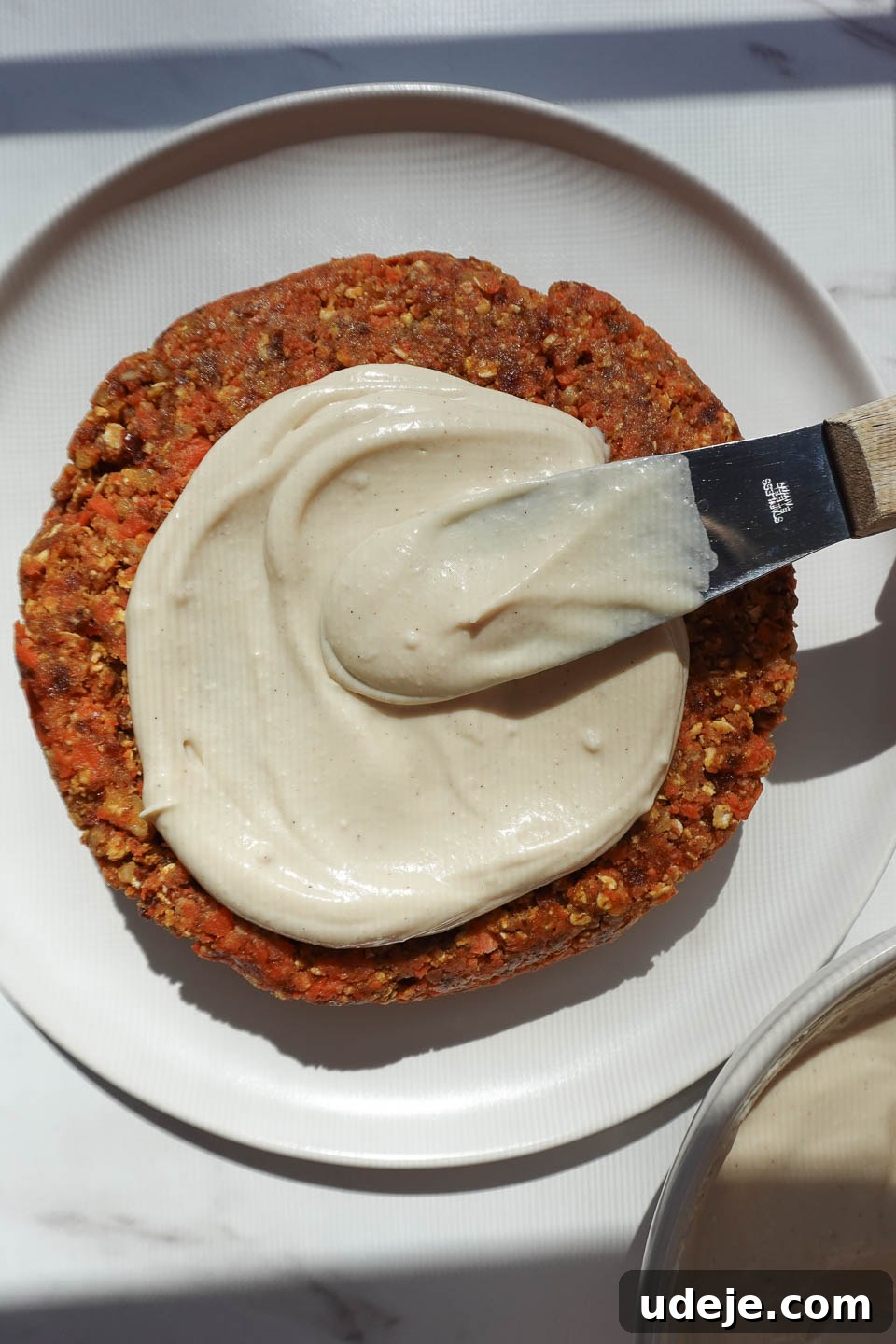 Dreamy No Bake Carrot Cake 14 Spreading vegan cream cheese frosting over no bake carrot cake with a spatula