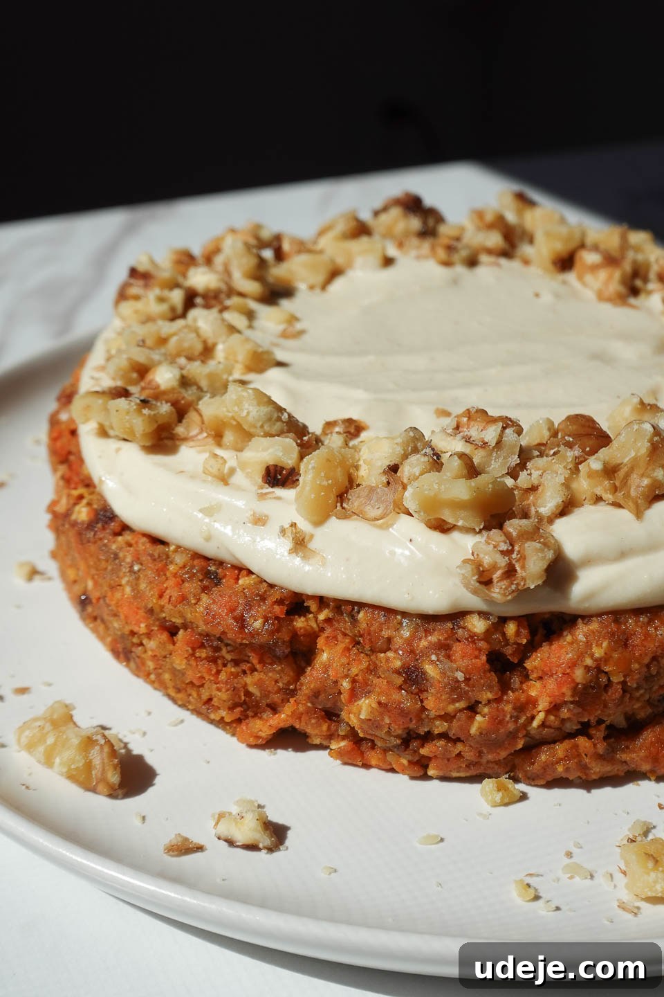 Dreamy No Bake Carrot Cake 15 Close up of vegan carrot cake with vegan cream cheese frosting and garnished with crushed walnuts for serving