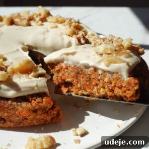 healthy no bake carrot cake topped with a vegan cream cheese frosting and crushed walnuts being sliced and served