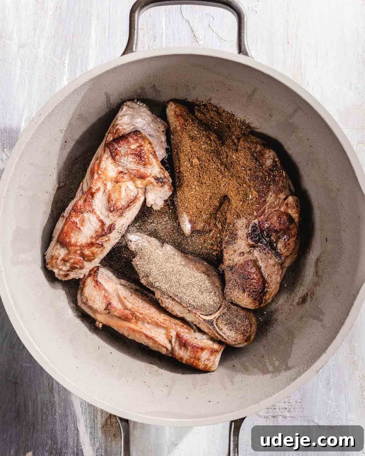 Kabuli Pulao: Slow-Cooked Afghan Lamb and Spiced Rice Recipe 8 A white pot containing browned pieces of meat seasoned with a generous amount of ground spices on top, seen from above.