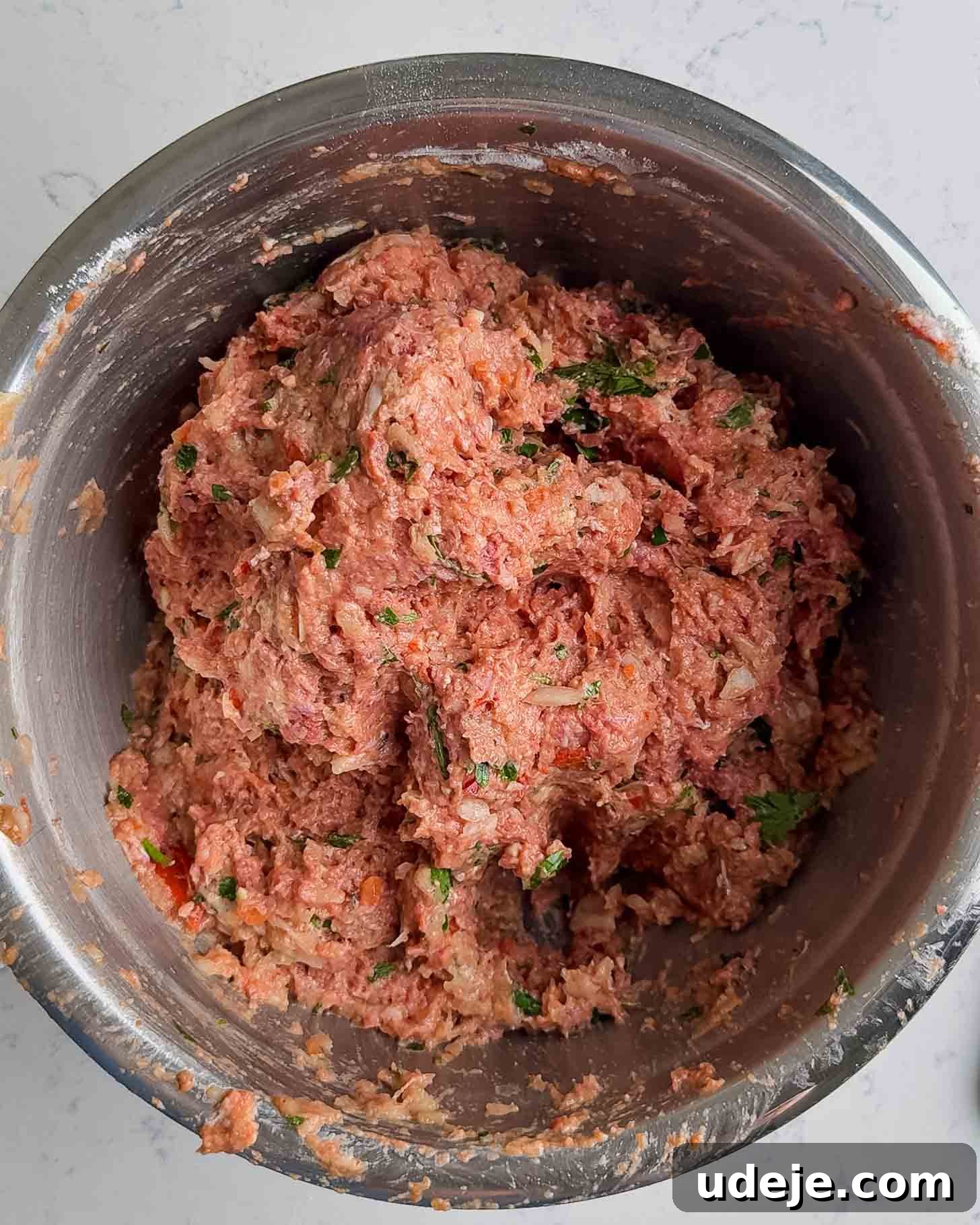 Juicy Ground Beef Sheet Pan Kebabs: Quick Oven Dinner 6 A stainless steel bowl filled with a mixture of raw ground meat, herbs, and seasonings, ready to be prepared for cooking.