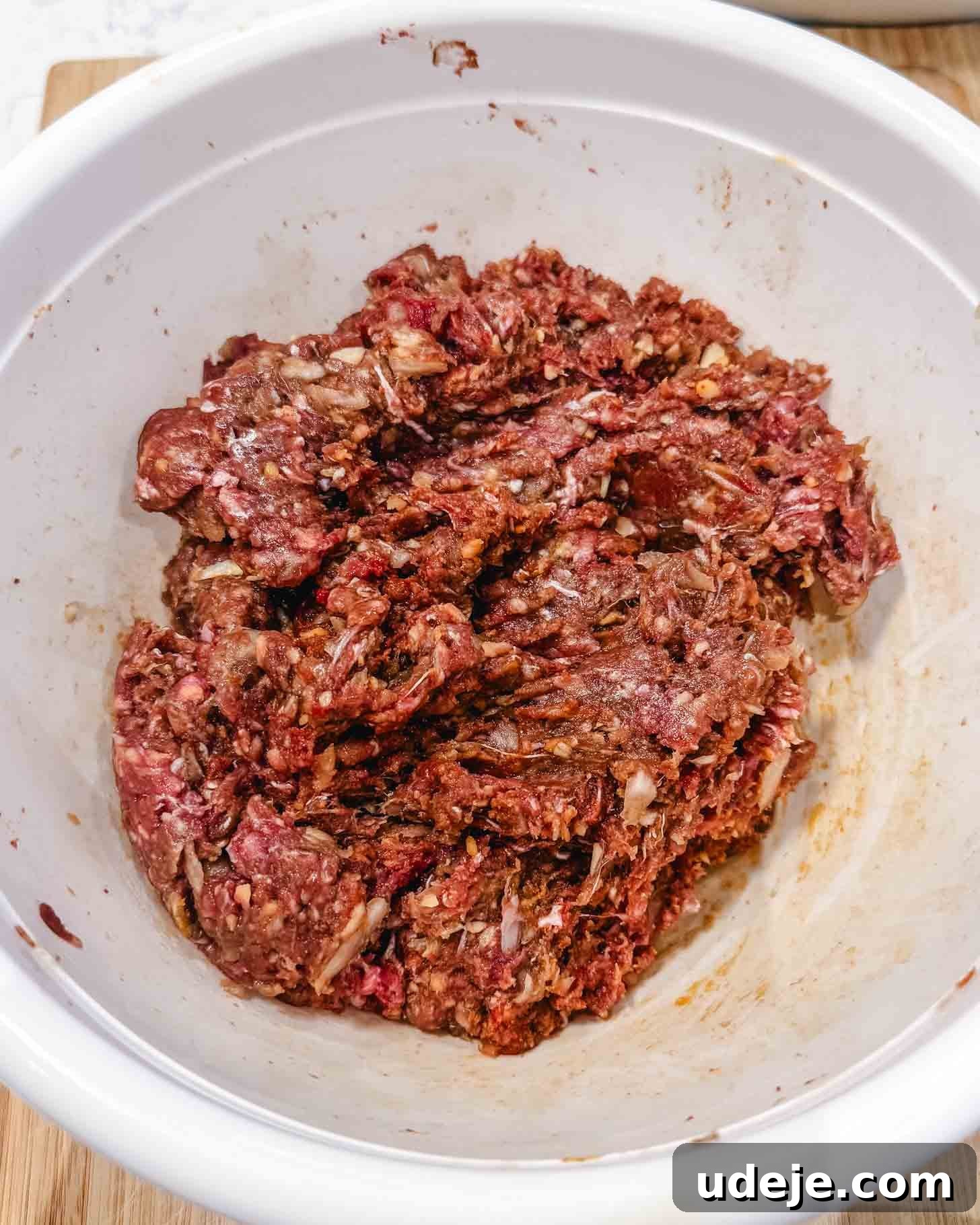 Weeknight Beyti Kebab with Warm Tortillas 4 Raw ground beef mixed with seasonings and oats in a white mixing bowl, ready to be used for a recipe such as meatloaf or meatballs.
