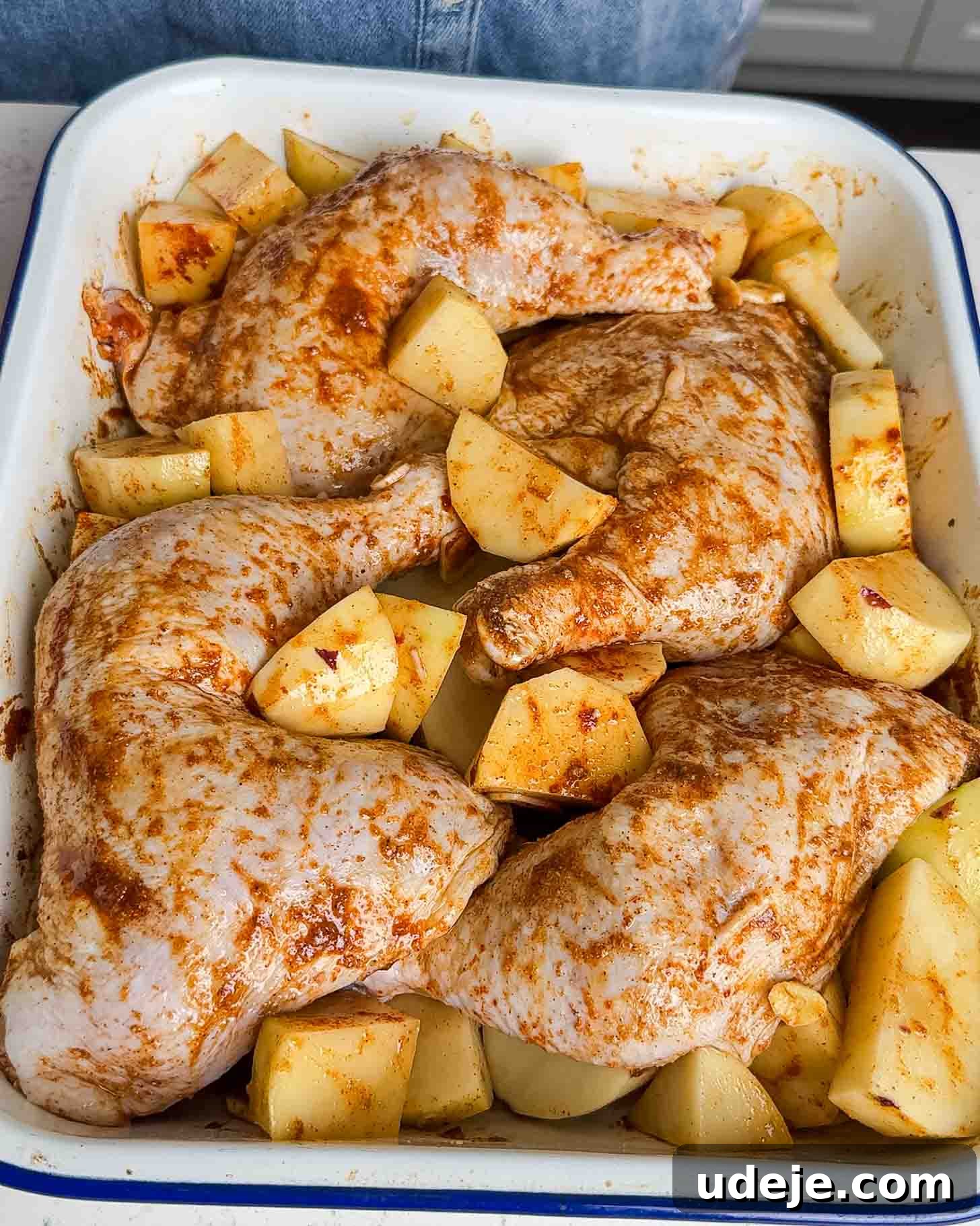 Roasted Lemon Garlic Chicken with Irresistible Pan Juices 6 Raw, seasoned chicken legs with spices arranged in a baking dish, surrounded by chopped potato pieces, ready to be cooked.