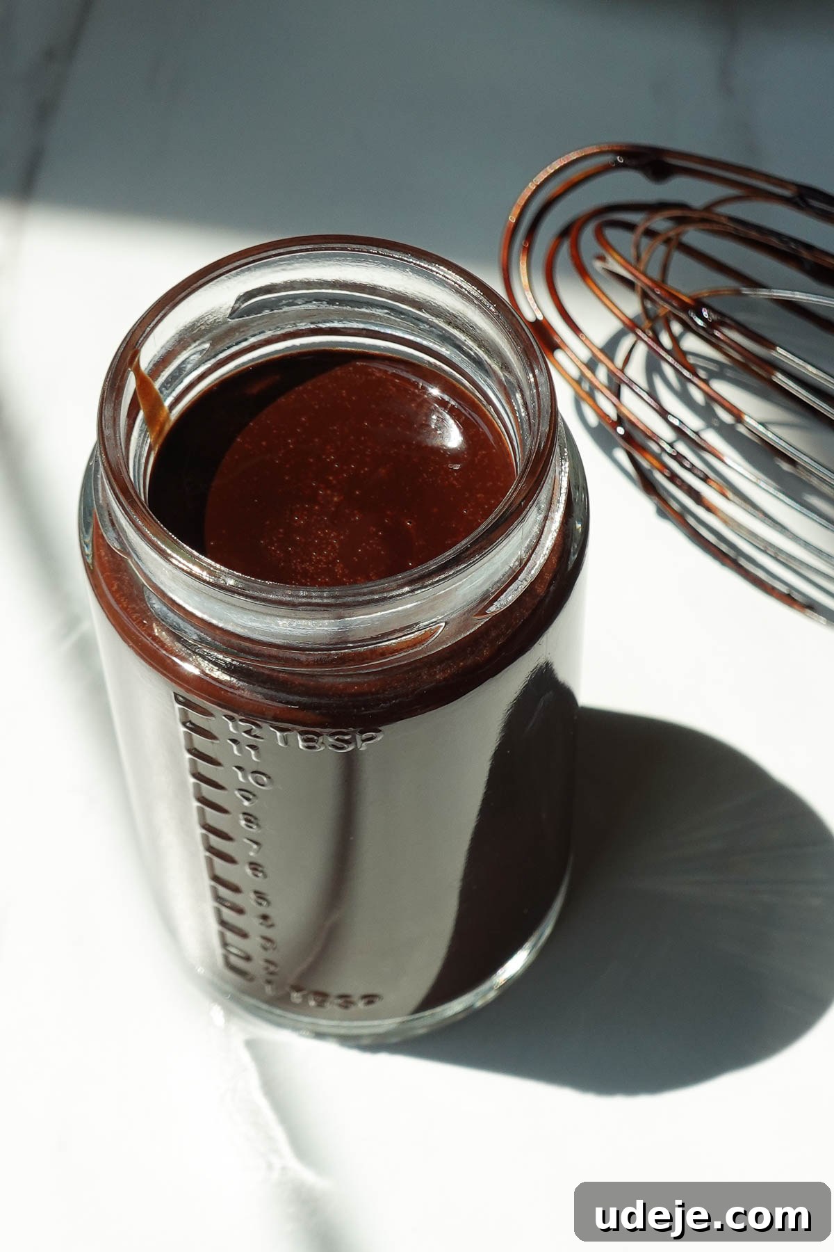 Freshly made chocolate syrup cooling in a glass jar before thickening.