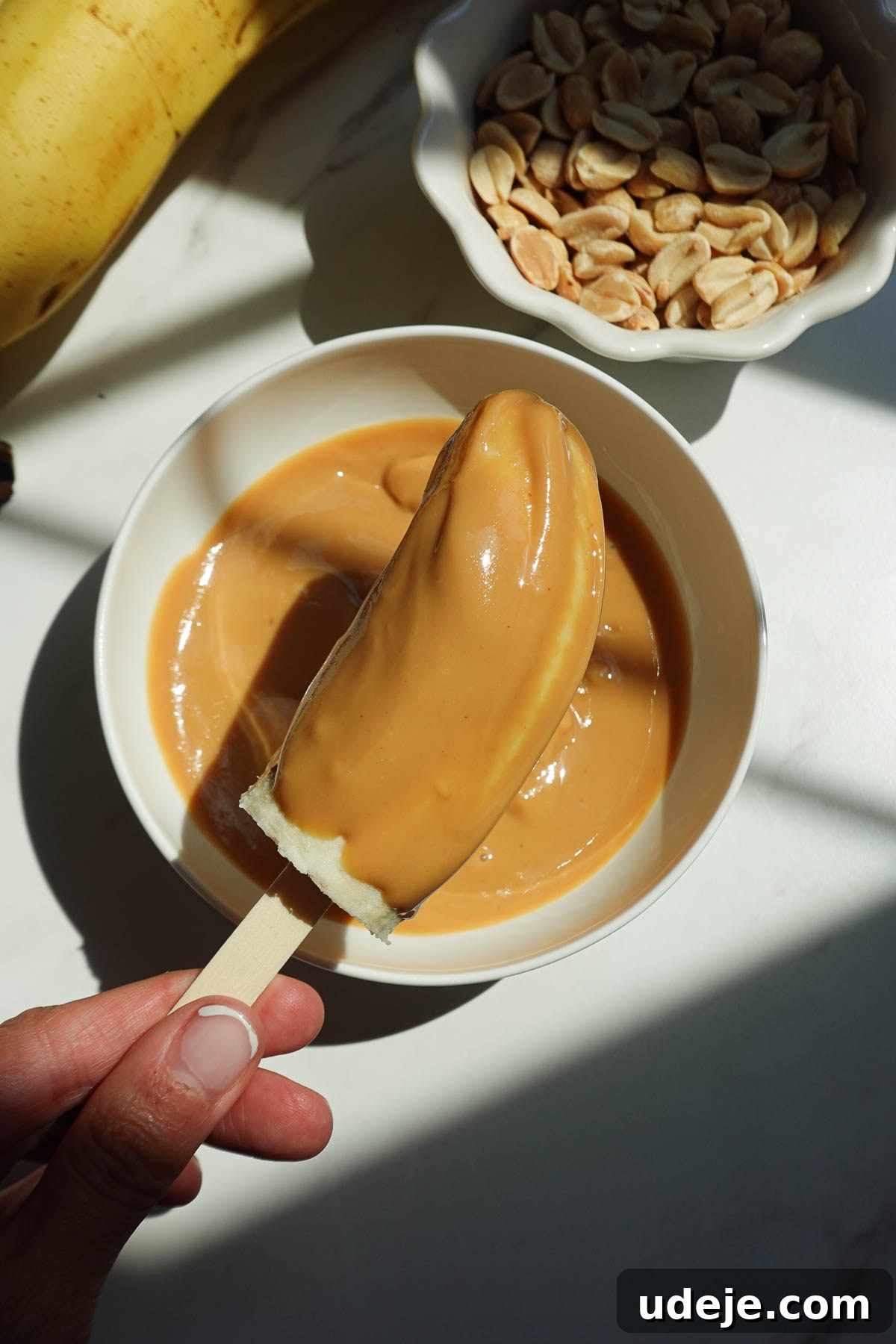 Snickers-Stuffed Frozen Banana Pops 7 Spreading peanut butter on banana halves