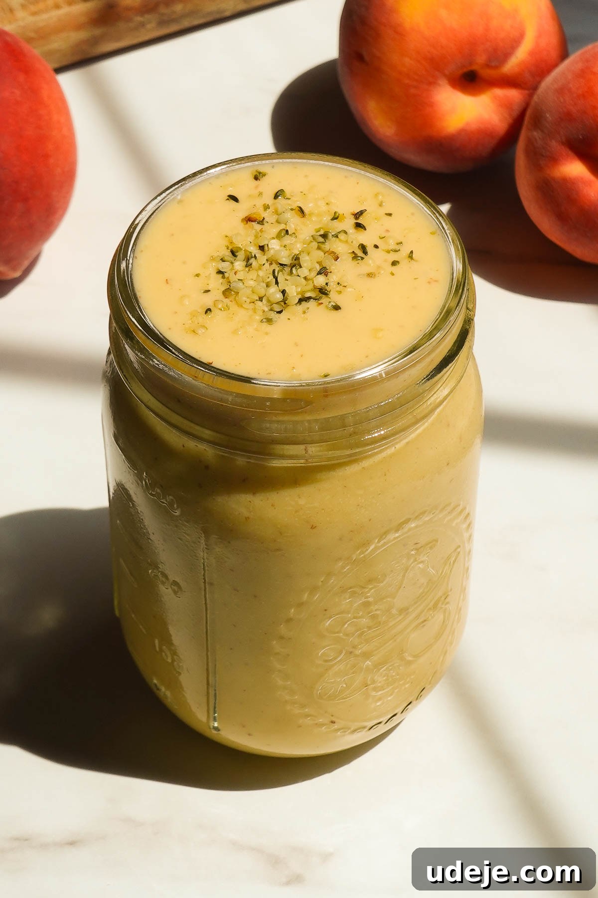 Creamy peach mango smoothie served in a glass.