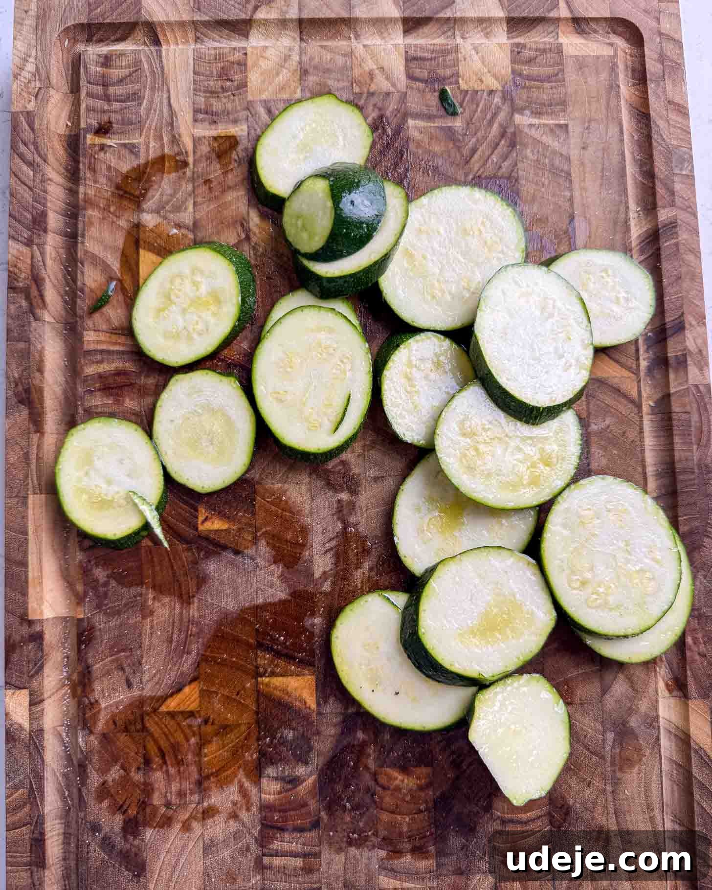 Sliced zucchini rounds are spread out on a wooden cutting board.